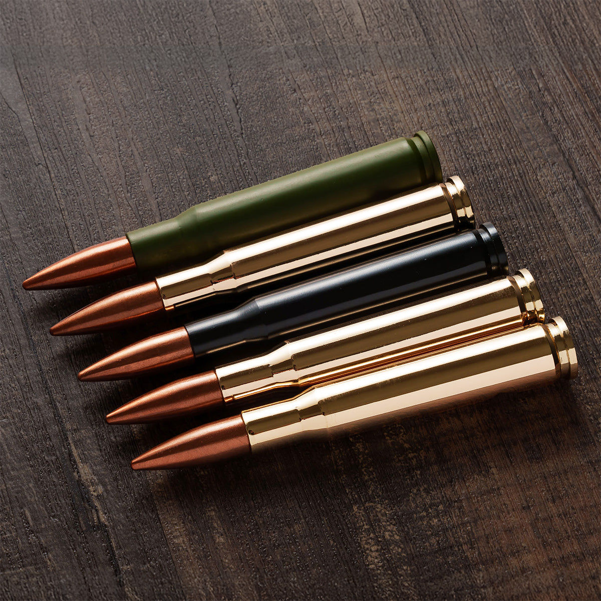 Green, gold and black bullet bottle openers laid on a wood table