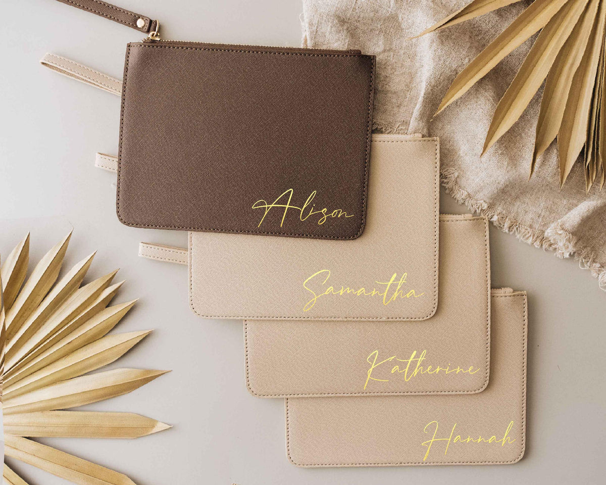 Set of personalized oat and mocha clutch bags with gold bridesmaid names