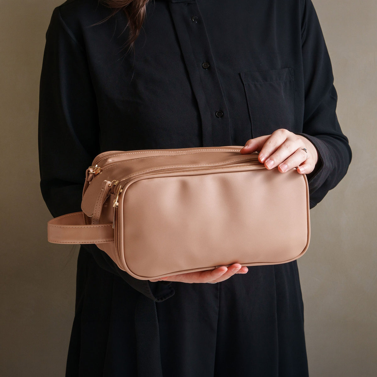 Woman holding the khaki cosmetic bag to show its size