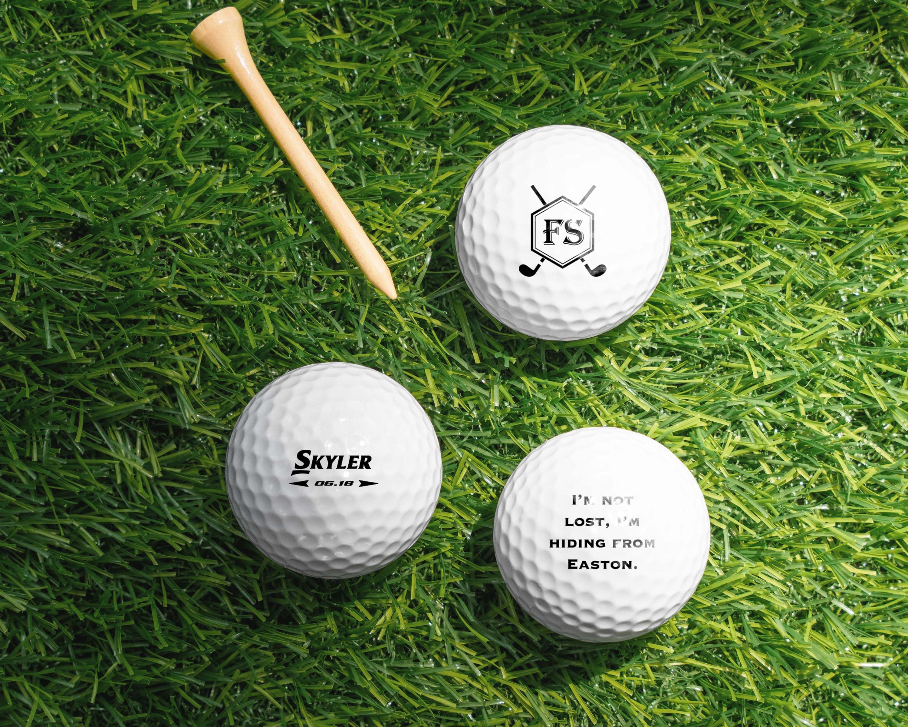 three golf balls and a wooden tee laying on the grass