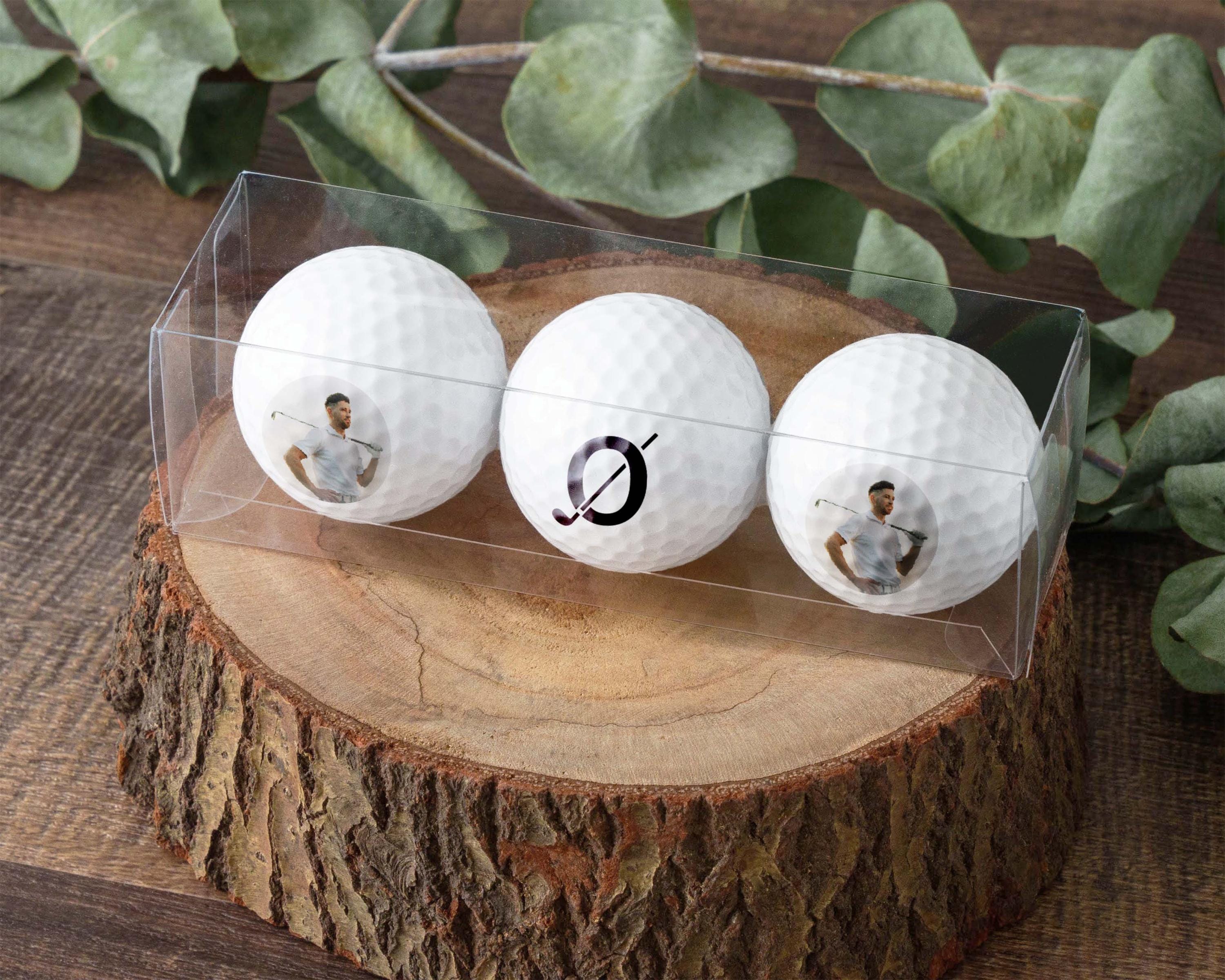 three golf balls in a clear case on a tree stump