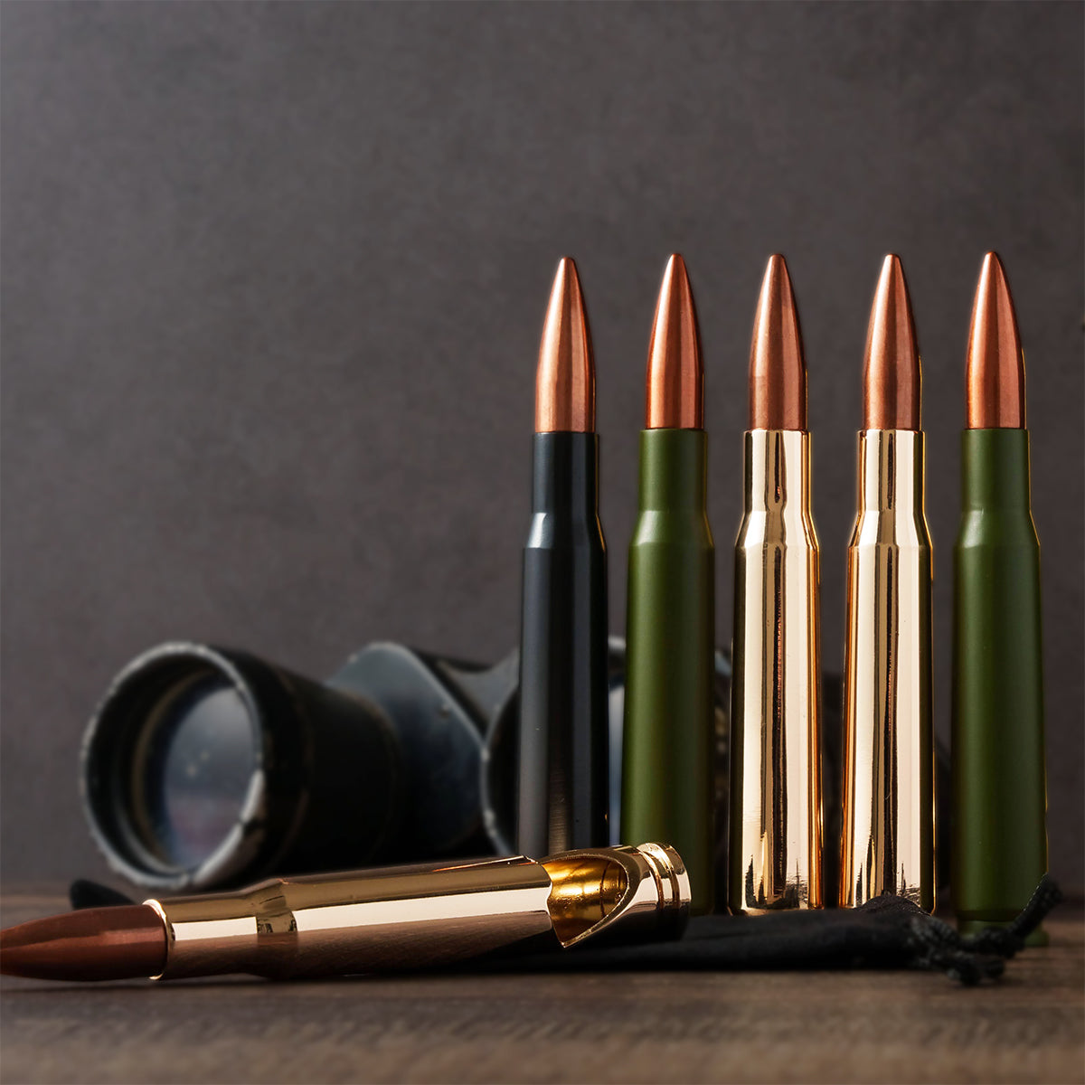 Bullet bottle openers in black, green and gold beside a camera lens