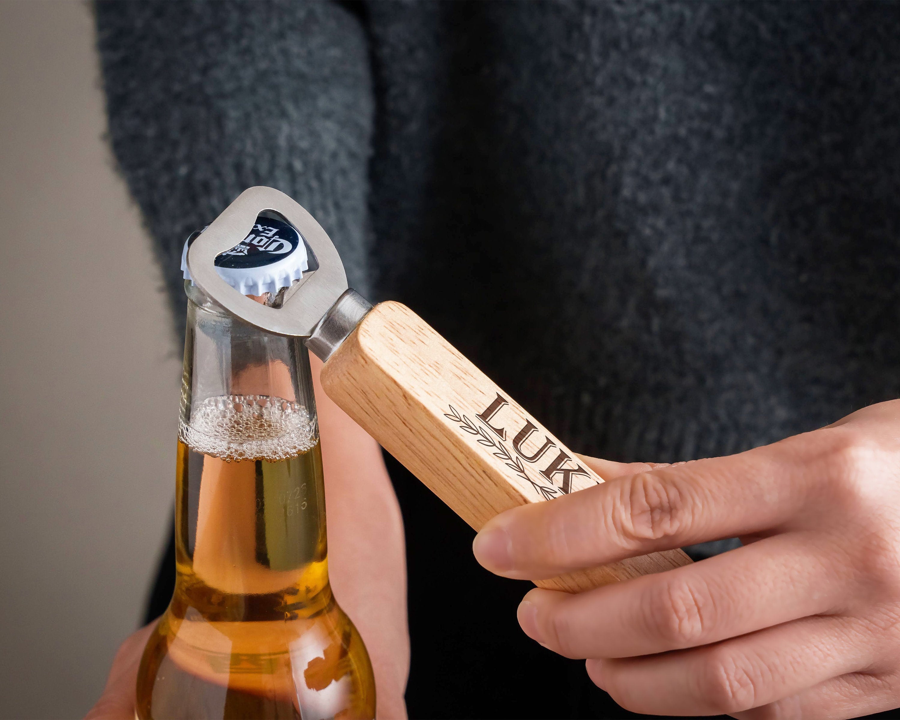 a person holding a bottle opener with a beer in it