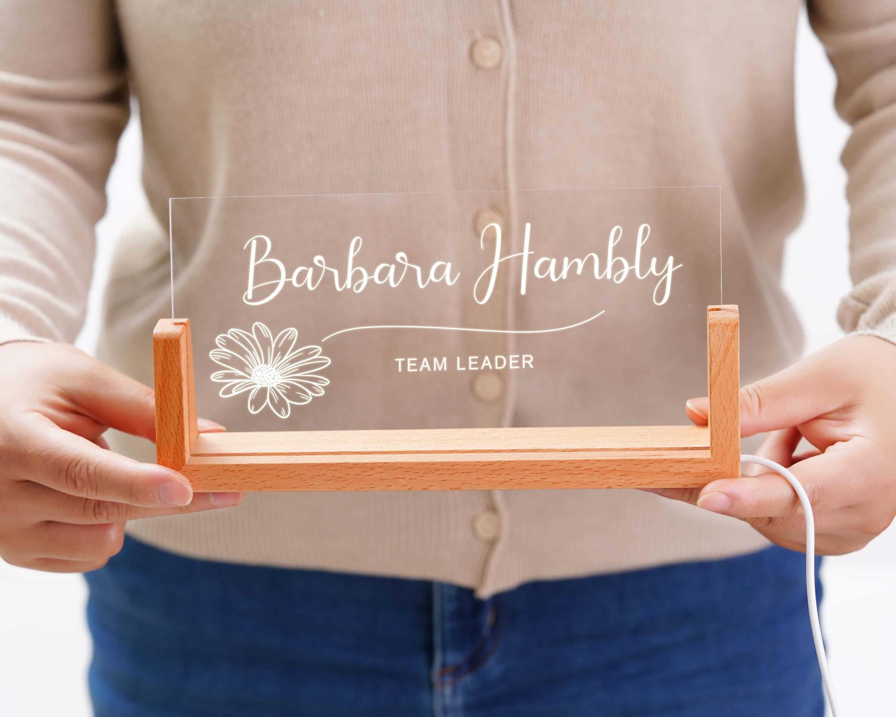 a person holding a clear acrylic sign with a flower on it