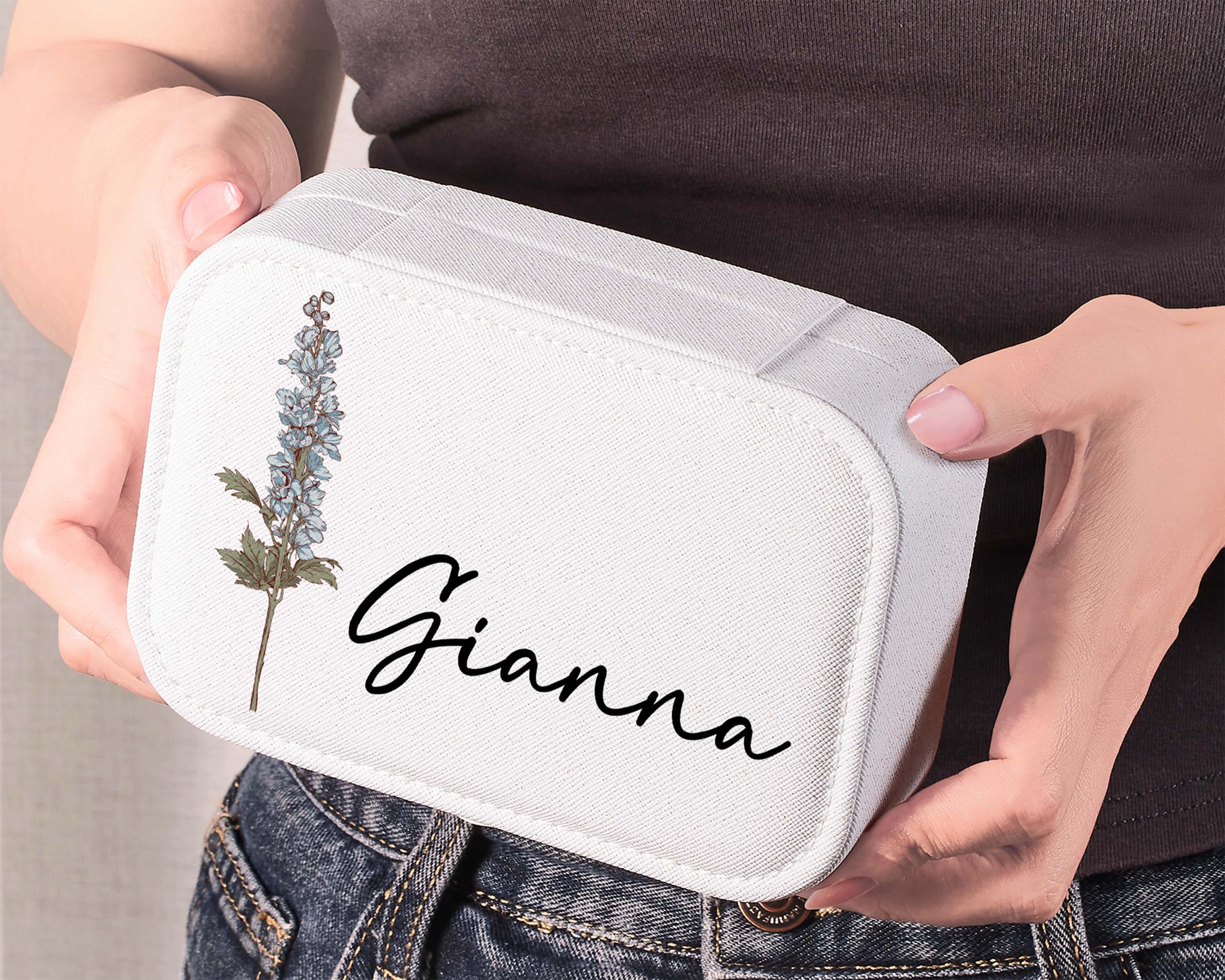 a woman is holding a white box with a picture of a flower on it