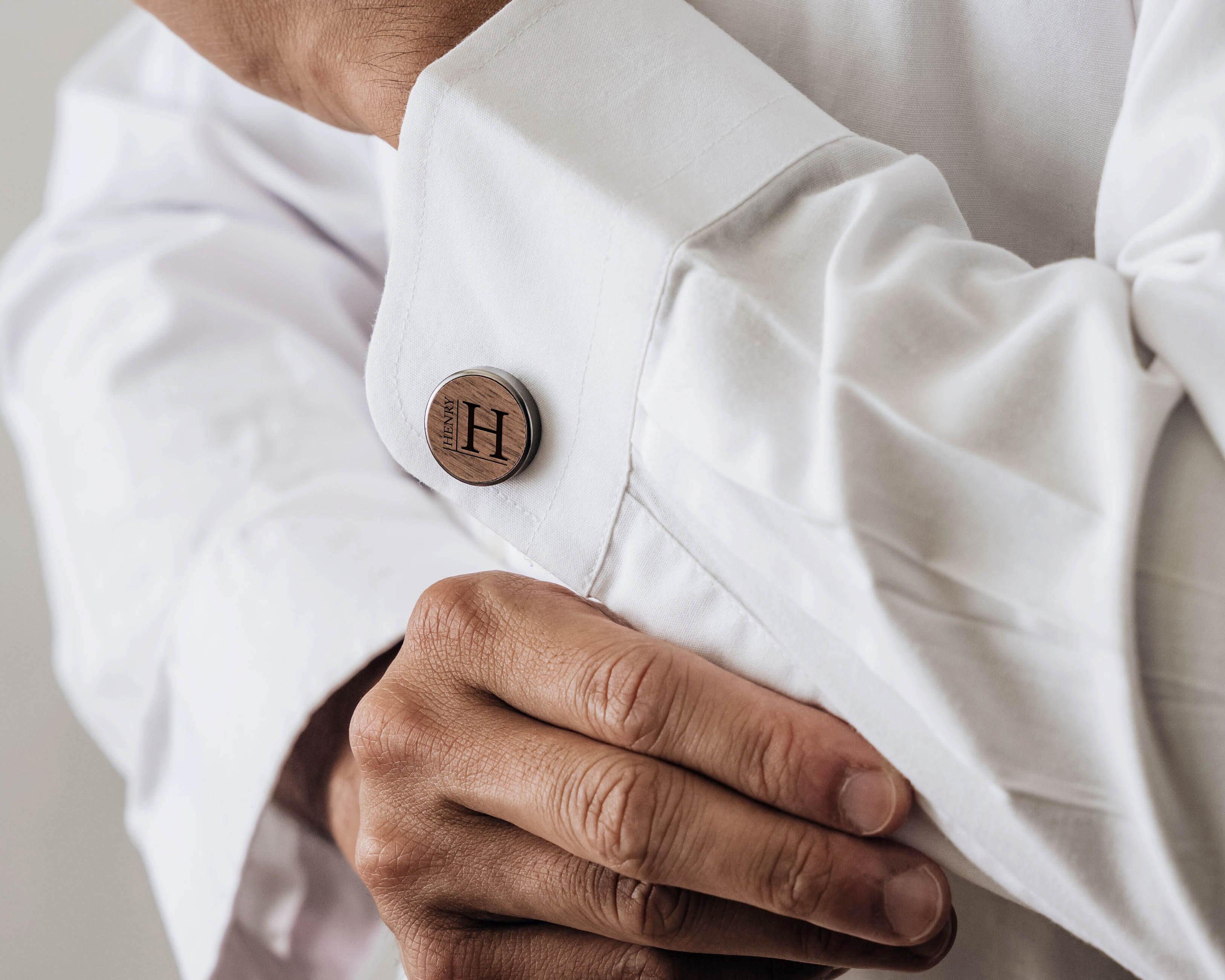 A men wear wooden cufflinks with custom initials on his shirt.